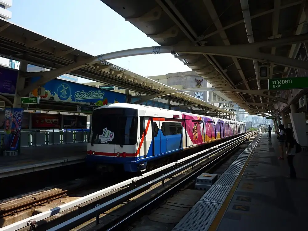 A BTS Skytrain at the elevated platform of Chit Lom station in daylight